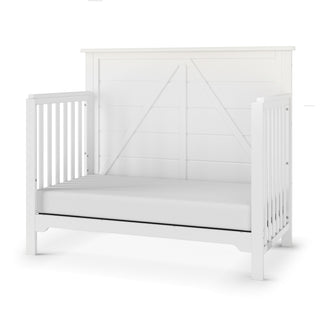 The Child Craft Woodland 4-in-1 Convertible Crib in Brushed Cotton features a paneled headboard and vertical slats, shown without the front rail for a toddler bed look. Its simple, modern farmhouse style complements any nursery.