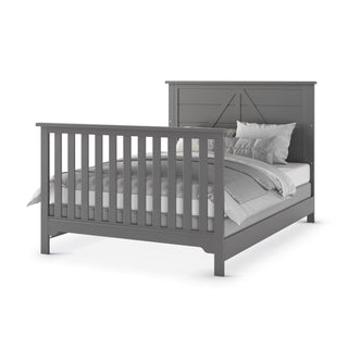 The Child Craft F06401 Full-Size Bed Rails in Brushed Pebble, made of durable pine wood, are shown with a gray wooden bed frame featuring a tall slatted footboard and decorative headboard, set against a white background.