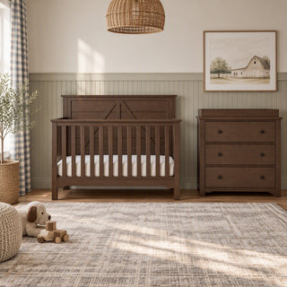 A Child Craft Woodland 4-in-1 Convertible Crib in Brushed Truffle with a farmhouse-style headboard and a matching three-drawer dresser in a nursery.