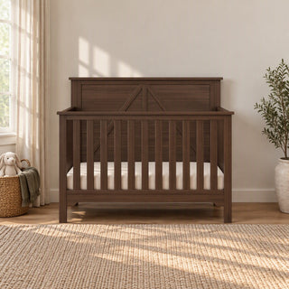 Child Craft Woodland 4-in-1 Convertible Crib in Brushed Truffle featuring a dark wood, barn door-style headboard and adjustable mattress support.