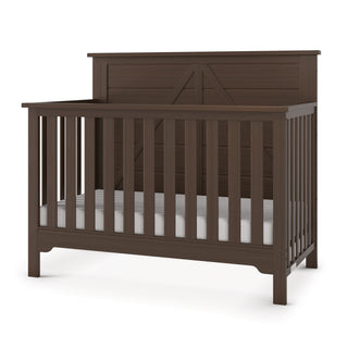 The Child Craft Woodland 4-in-1 Convertible Crib in Brushed Truffle features dark brown pine wood, vertical slats, a solid headboard with panel details, and adjustable mattress support. Shown on a white background.