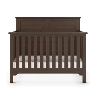 The Child Craft Woodland 4-in-1 Convertible Crib in Brushed Truffle features dark brown pine wood, vertical slats, a solid geometric headboard, and adjustable mattress support, shown on a white background.