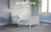 The Child Craft Hampton Toddler Bed in Matte White features shiplap paneling, a slatted headboard and footboard, built-in guard rails, an arched design, sturdy wood construction, and a low profile for easy access.