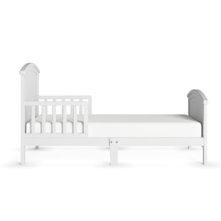 The Child Craft Hampton Toddler Bed in Matte White is a low-profile bed with a guard rail on one side, simple headboard and footboard, and includes a mattress. Shown against a plain white background.