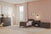 A cozy toddler bedroom with light pink walls, a Child Craft Hampton Toddler Bed in Dapper Gray featuring guard rails, plus a dresser, nightstand, toy chest, and rocking horse. White-curtained window and animal prints complete the décor.