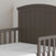 A close-up view of the Child Craft Hampton Toddler Bed in Dapper Gray with sturdy guard rails and a white crib mattress, set against a light-colored wall.
