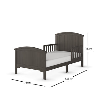 The Child Craft Hampton Toddler Bed in Dapper Gray features slatted sides, built-in guard rails, and an arched headboard and footboard. Includes a white crib mattress. Dimensions: 76 cm H x 142 cm L x 78 cm W.