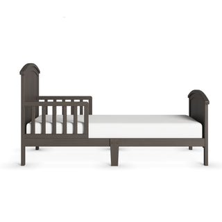 The Child Craft Hampton Toddler Bed in Dapper Gray features partial left guard rails and an arched headboard and footboard. Shown from the side with a crib mattress on a white background.