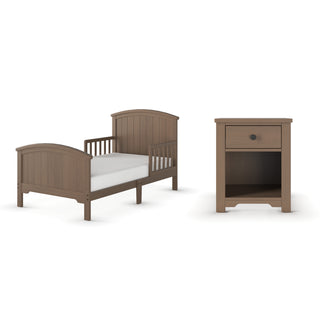The Child Craft Hampton Toddler Bed in Dusty Heather features a high headboard and footboard, paired with a matching nightstand that has one drawer and an open shelf, all in a light brown finish.