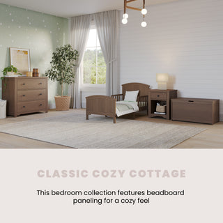 A cozy bedroom with the Child Craft Hampton Toddler Bed in Dusty Heather, wood furniture, light green dot wallpaper, white beadboard walls, a window with curtains, a rug, and décor. Text reads: Classic Cozy Cottage with beadboard paneling for comfort.