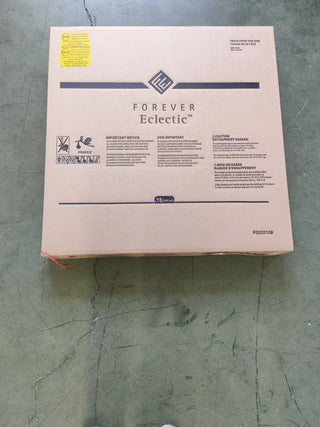 A large cardboard box labeled “Child Craft” sits on a green tiled floor. The packaging displays the Hampton Toddler Bed, Cool Gray with guard rails, plus caution notices and instructions in English and French.