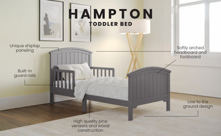 The Child Craft Hampton Toddler Bed in Cool Gray features shiplap paneling, an arched headboard and footboard, built-in guard rails, and a low-profile design, perfect for a cozy, minimalist nursery.