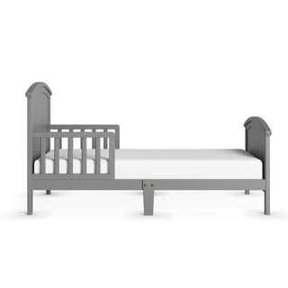 The Child Craft Hampton Toddler Bed in Cool Gray is low to the ground, features side guard rails, and comes with a white mattress. Shown from the side on a white background.