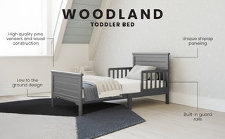 The Child Craft Woodland Toddler Bed in Brushed Pebble features a low profile, sturdy pine construction, built-in guard rails, and fits a standard crib mattress—perfect for modern bedrooms with shiplap paneling and sloped ceilings.