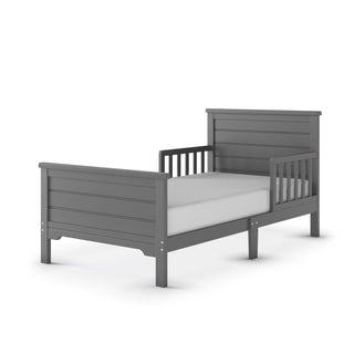 The Child Craft Woodland Toddler Bed in Brushed Pebble, featuring a slatted headboard, footboard, and toddler bed rails, is shown on a white background with a crib mattress.