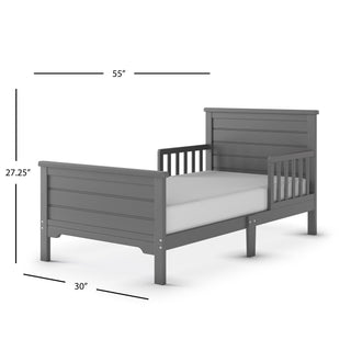 The Child Craft Woodland Toddler Bed in Brushed Pebble features a gray wooden frame, slatted headboard and footboard, sturdy toddler rails, and fits a crib mattress. Dimensions: 55" L x 30" W x 27.25" H.