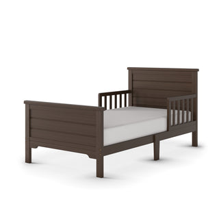 The Child Craft Woodland Toddler Bed in Brushed Truffle features a dark brown finish, high headboard, low footboard, side rails, and a white mattress, all set against a plain white background.
