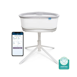 The HALO BassiNest® Connected Swivel Sleeper 3.0, a modern white smart bassinet with light gray lining on a tripod stand, features AutoSoothe tech, Baby Safety Verified badge, and connects to a baby monitoring app via smartphone.