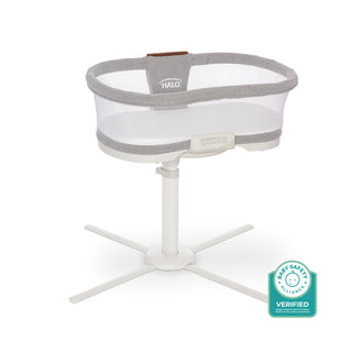 A HALO BassiNest® Luxe Swivel Sleeper Bassinet in gray and white with mesh sides and a white swivel base is shown beside a Baby Safety Alliance Verified badge.