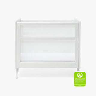 The HALO Mini Breathable Mesh Crib, a modern white compact crib with mesh sides and a solid mattress, is pictured on a plain background. A green GREENGUARD Gold certification badge appears in the bottom right corner.