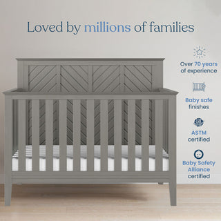 The Child Craft Atwood 2-Piece Crib and DreamWeave Set in Lunar Grey is displayed against a beige wall with “Loved by millions of families” above. Features: years of experience, baby-safe finishes, ASTM certified, and compatible with HALO DreamWeave mattress.