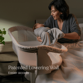 A woman places a swaddled baby into a HALO BassiNest® Swivel Sleeper 4.0 Air with Dreamweave Breathable Pad, featuring a patented lowering wall for easier access, next to a bed. Text reads: Patented Lowering Wall. Easier Access.