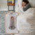 A smiling woman lies in bed under a white comforter, next to a HALO 2-in-1 Bedside Bassinet Sleeper with a swaddled baby inside. Text reads: Attaches to your bed for extra close sleep.