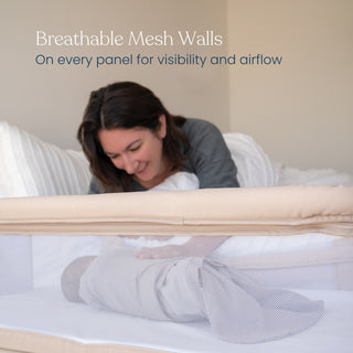 A woman smiles at a baby lying in a HALO 2-in-1 Bedside Bassinet Sleeper with breathable mesh walls. Text on the image reads: Breathable Mesh Walls — On every panel for visibility and airflow.