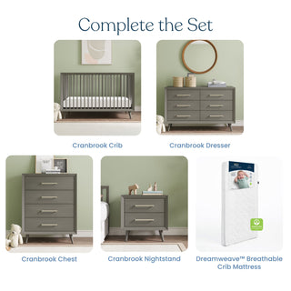 Set of nursery furniture featuring a gray crib, Child Craft Cranbrook Double Dresser in Lunar Gray, chest, nightstand, and white Dreamweave™ breathable crib mattress, all displayed against a light green wall.