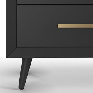 Close-up of the Child Craft Cranbrook Double Dresser in Ebony shows an angled leg and a drawer with a gold horizontal handle. Set against a white background, this modern nursery piece features a sleek, minimalistic design.