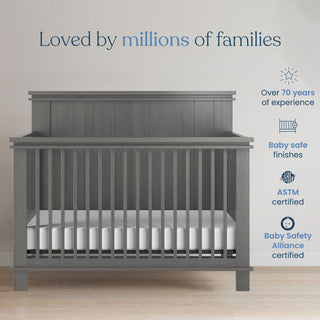 A Child Craft Denman 2-Piece Crib and DreamWeave Set in Midnight Grey stands on a wooden floor by a light wall. Text highlights safety, certifications, and experience, with convertible crib features shown beside blue and gray icons.