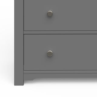 Close-up of the lower half of the Child Craft Harmony 3-Drawer Dresser with Changing Table Topper in Cool Gray, showing two drawers with round metallic knobs and part of the left edge and base.