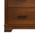 A close-up of the bottom corner of the Child Craft Redmond 3 Drawer Dresser in Coach Cherry, featuring two drawers with black metal handles and a dark base trim—ideal for nursery storage.
