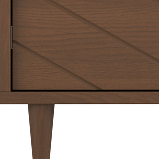 Close-up of the Surrey Hill 5 Drawer Chest by Child Craft in Toasted Chestnut, showing the textured wood corner with angled grooves, a diamond-patterned drawer front, and tapered leg for a modern geometric look.
