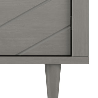 Close-up of the Child Craft Surrey Hill 5 Drawer Chest in Lunar Gray, highlighting its diagonal groove design and single tapered leg, with part of the door’s edge and hinge visible.