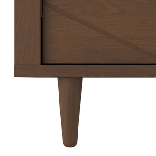 Close-up of the bottom corner of the Child Craft Surrey Hill 3 Drawer Dresser in Toasted Chestnut, showing its tapered leg and diagonal groove detail on the drawer front with a smooth, medium brown finish.