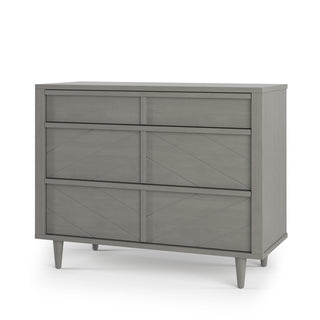 The Child Craft Surrey Hill 3 Drawer Dresser in Lunar Gray features angled legs and subtle geometric front panels, offering a modern, chic storage solution for your nursery.