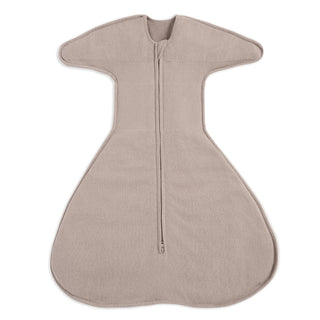 The HALO SwaddleStretch™ Newborn Swaddle TOG 0.5 is a beige, sleeveless sleep sack with a wide, rounded bottom, wing-like shoulders, and a center zipper from neck to edge for easy use. It’s hip-healthy and perfect for newborns.