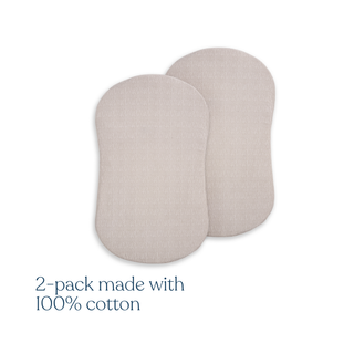 Two beige oval pads, resembling HALO BassiNest® Fitted Sheet 100% Organic Cotton 2-Pack, are side by side on a white background. Lower left text reads, "2-pack made with 100% organic cotton.