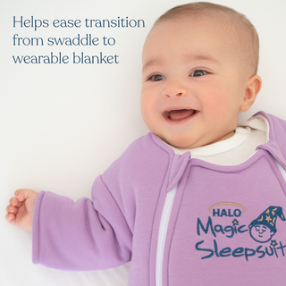 A smiling baby in a lavender Baby Merlin's Magic Sleepsuit® 100% Cotton by HALO lies on a white surface. Text reads: Eases swaddle transition and supports better sleep for babies.
