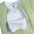 A close-up of a light green Baby Merlin's Magic Sleepsuit® 100% Cotton by HALO, featuring two partially open zippers and a white flap reading 