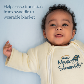 A smiling baby lies on a light blue surface wearing the HALO Baby Merlin's Magic Sleepsuit® 100% Cotton. Text beside the baby reads, Helps ease transition from swaddle to wearable blanket for a smoother swaddle transition.
