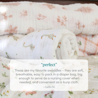 Four soft, white aden + anais essentials cotton muslin swaddle blankets with floral and animal prints are rolled and layered. A text box below highlights their softness, breathability, versatility, and convenience for parents.