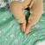 A babys tan pants rest on a soft, playful green blanket resembling the Disney™ essentials cotton muslin swaddle blanket by aden + anais, adorned with light cartoon animals and toys in thin lines, echoing warmth and softness.