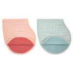 Two aden + anais organic cotton muslin burpy bibs are shown side by side: a peach GOTS certified bib with a coral inner layer on the left, and a mint green one with a teal inner layer on the right. Both have soft, quilted textures and curved shapes.