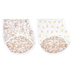 The aden + anais boutique silky soft burpy bib 2 pack includes two bibs with brown and yellow patterns: one with a floral design and another with a small yellow fruit motif. Both feature a 2-in-1 absorbent burp cloth with brown-and-white fabric on the bottom.