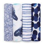 The aden + anais boutique 100% cotton muslin swaddle blanket 4 pack features four rolled-up blankets, each with a unique blue design: swirling waves, whale illustrations, stripes, and bold circles on white. These breathable swaddles ensure excellent absorbency for your babys comfort.