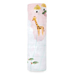 The aden + anais boutique 100% cotton muslin swaddle blanket is a breathable, rolled-up baby blanket featuring charming illustrations of a giraffe, trees, and small huts. It has a light grid pattern and is primarily white with soft pastel hues.
