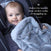 A smiling baby in a car seat with an aden + anais essentials plush blanket. Text says: Perfect for tummy time, stroller walks, or snuggling up. The baby wears a plush dark-colored outfit that complements modern colors beautifully.