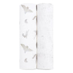 Two rolls of white fabric with subtle designs: gray bats and crescent moons on the left, and a dotted star pattern on the right. These soft, textured fabrics are ideal for creating aden + anaiss organic cotton muslin swaddle blanket 2 pack, which is GOTS certified.